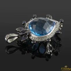COLGANTES Colgante realizado en oro blanco. Presenta un piedra azul principal con orla de brillantes.