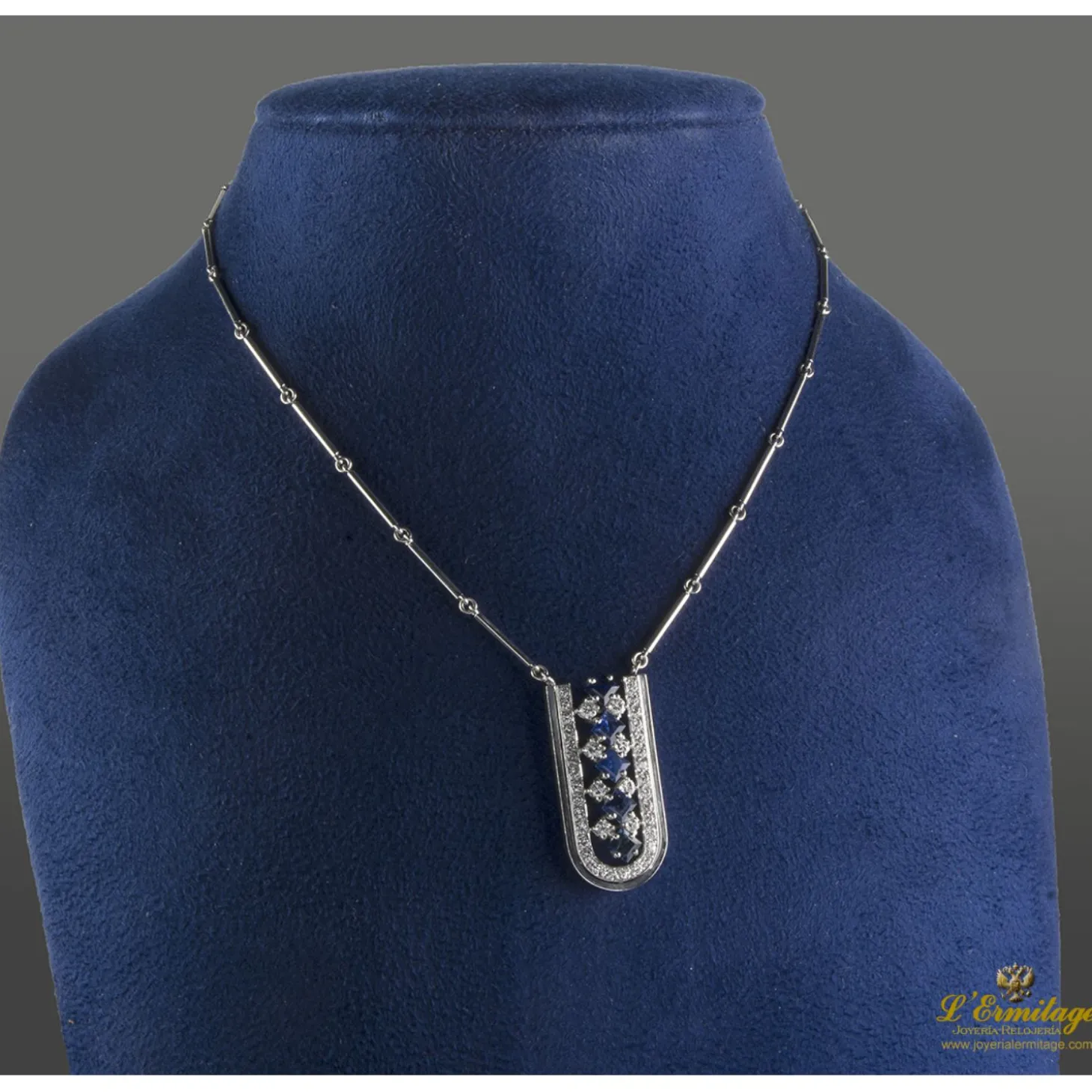 COLLARES Collar de barras cilíndricas realizado en oro blanco. Presenta colgante con zafiros y brillantes.