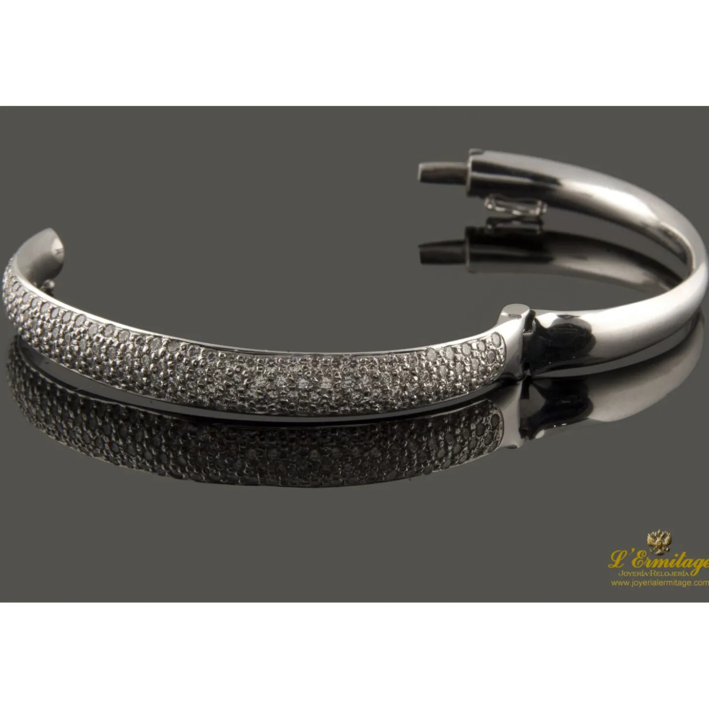 PULSERAS Pulsera rígida de media caña con centro pabe de brillantes montados en oro blanco.